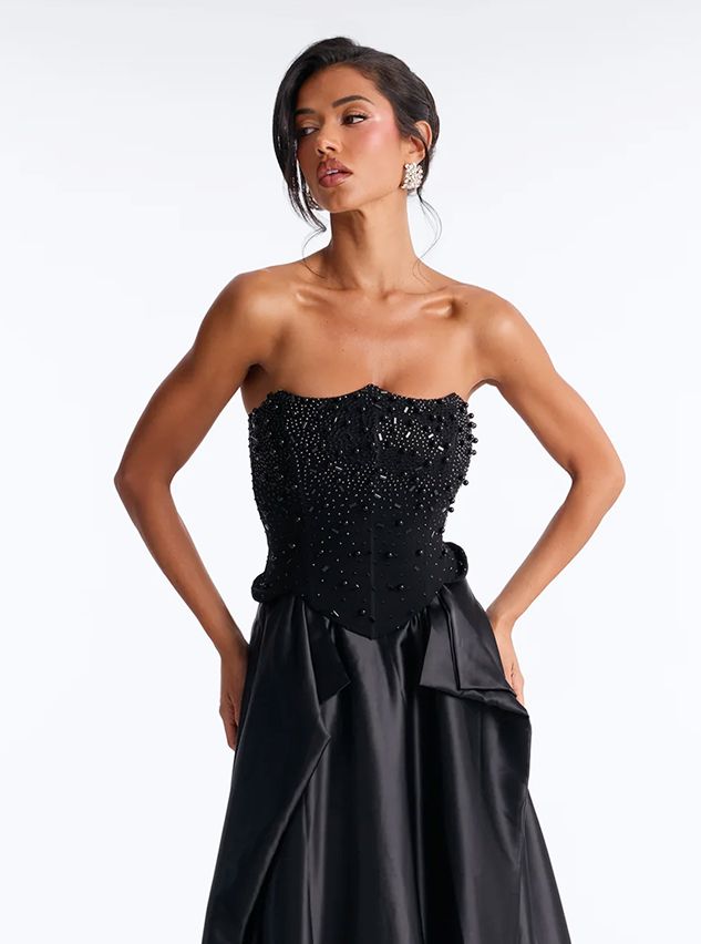 Woman posing in a luxury strapless black evening gown with a heavily beaded corset bodice and satin skirt, showcasing elegant partywear.