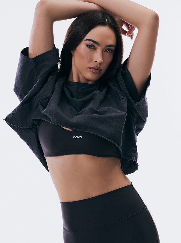 Mujer modelando top corto lavado oscuro y sujetador deportivo Nova con leggings a juego, mostrando estilo de ropa deportiva cómoda.