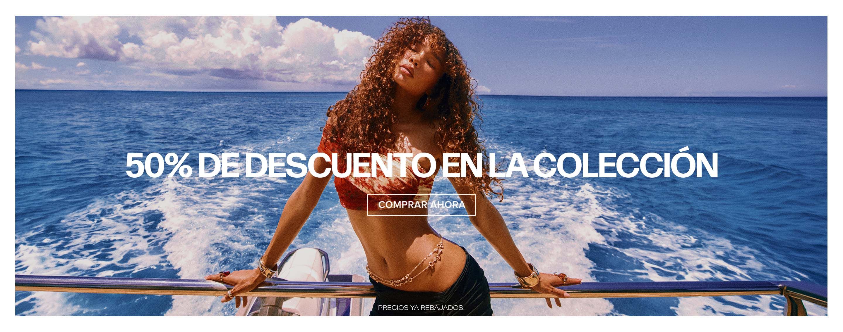 Mujer en yate con top rojo y falda negra, cabello al viento, océano azul. Promociona 50% de Colección Summer Refresh. ¡Compra ahora!
