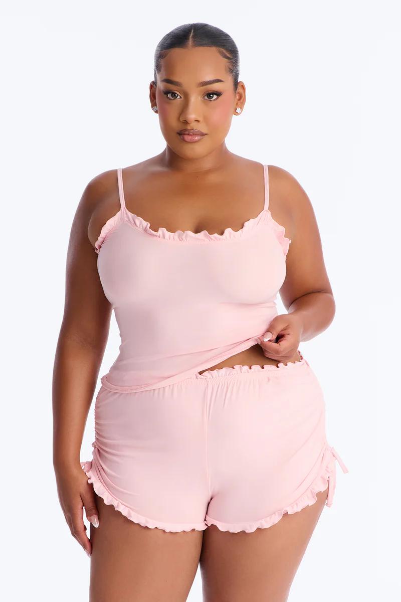 Plus size woman in pink ruffle cami & shorts pajama set. Comfortable curvy loungewear.
