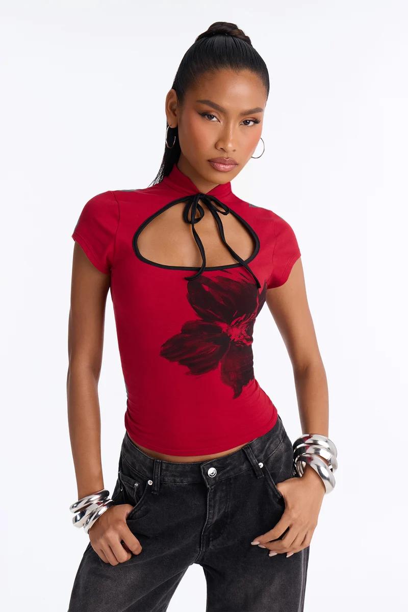 Mujer con top rojo de manga corta con abertura, estampado floral y cuello de lazo.