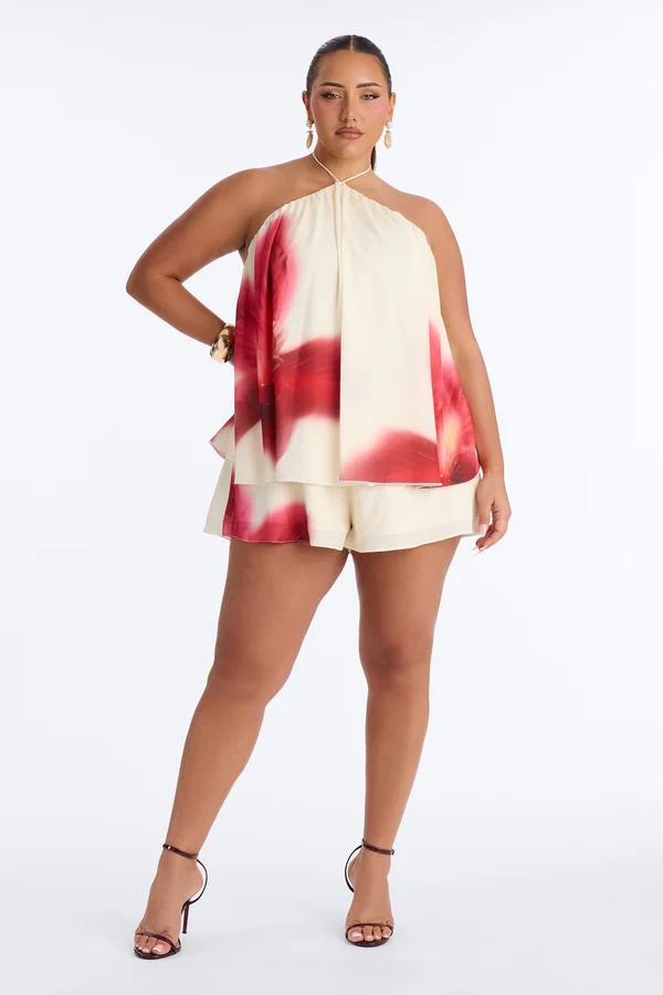 Elegant plus size model in a cream and red abstract floral halter top and matching shorts set, perfect for summer.