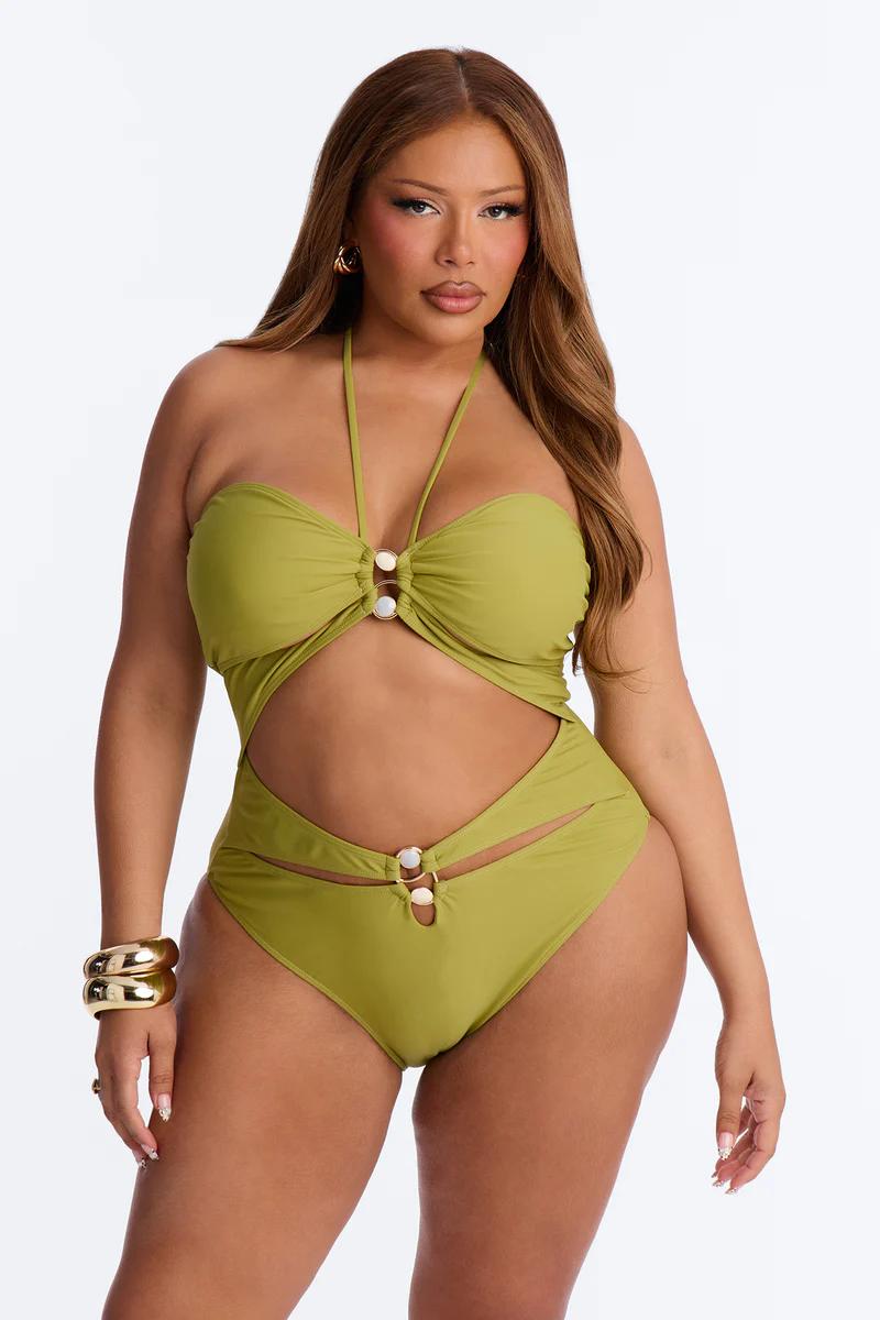 Curvy model in stylish olive green cutout one-piece swimsuit with gold accents. Flattering halter neck plus size swimwear.