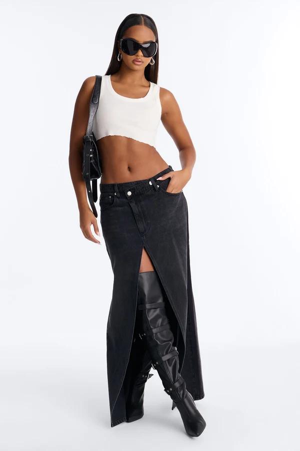 Trendy black denim maxi skirt with slit paired with a white crop top and thigh-high leather boots, showcasing a modern streetwear style.