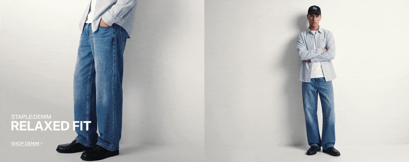 Man wearing a striped shirt and relaxed fit blue jeans to promote the staple men's denim collection. Shop casual straight and loose styles.