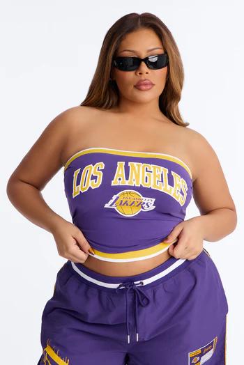 Woman wearing black sunglasses, a purple strapless top with "LOS ANGELES LAKERS" text and logo, and matching purple shorts.
