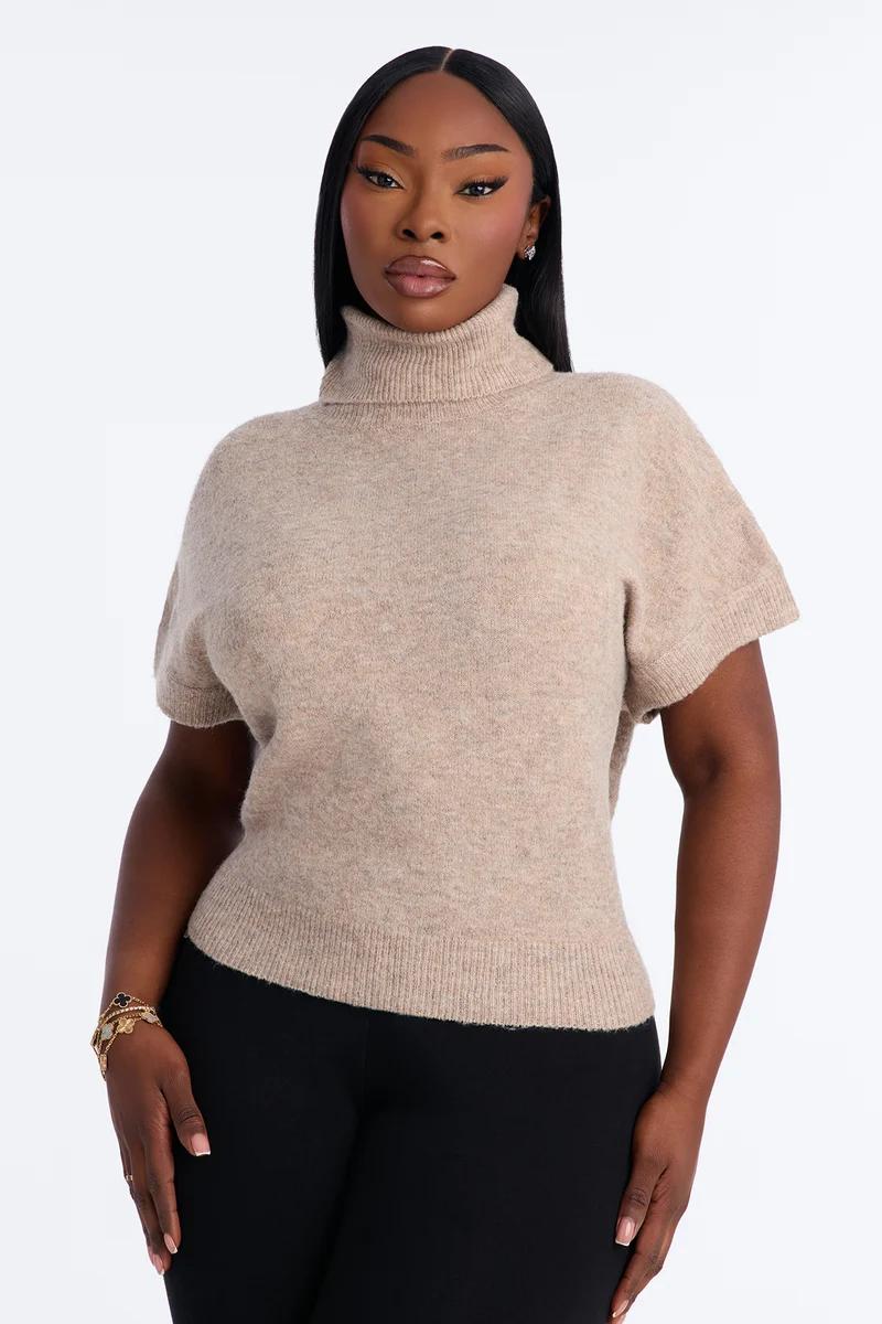 Mujer con suéter de punto beige con cuello alto y manga corta.