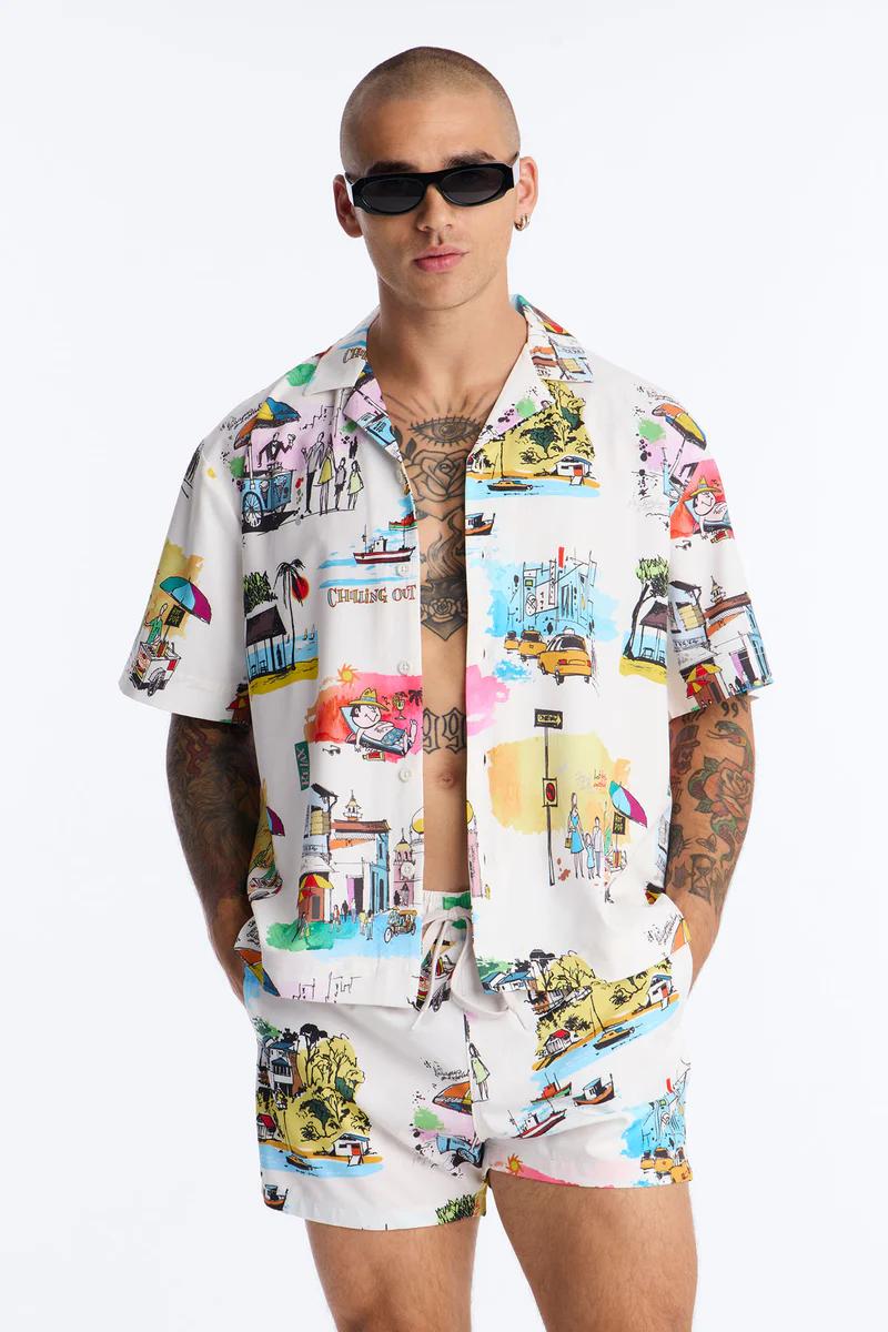 Hombre con camisa resort blanca y shorts de baño a juego, estampado "Chilling Out" de colores, para nueva moda de verano.