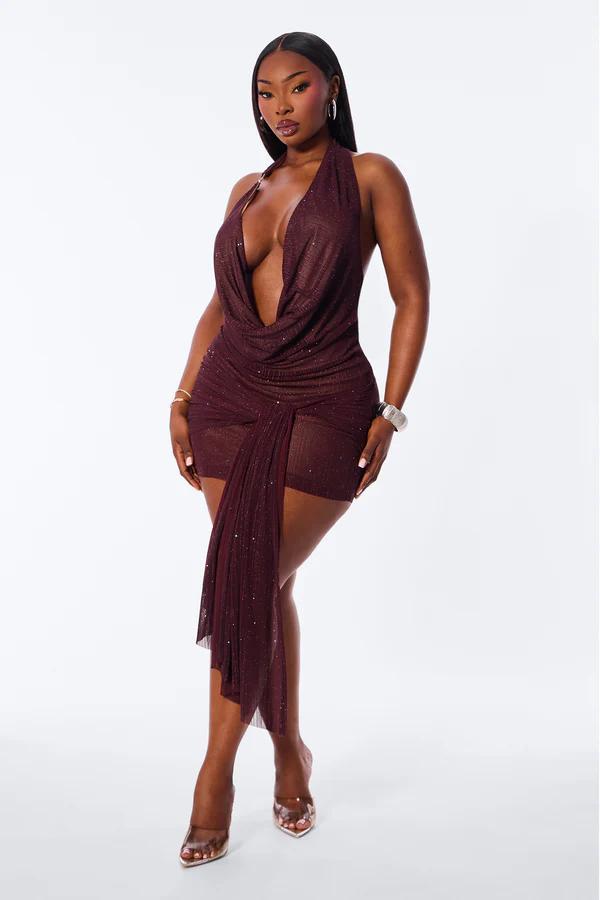 Mujer modelando un brillante mini vestido halter borgoña con cuello desbocado y panel lateral transparente, ideal para la noche.