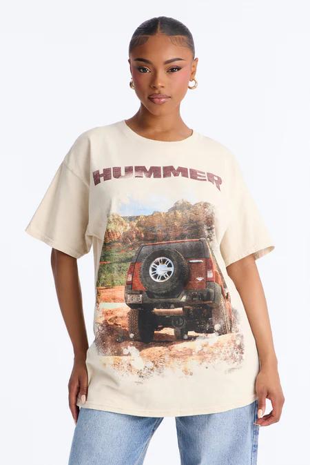 Woman in a beige t-shirt featuring a red 'HUMMER' graphic above a detailed rear view of a red SUV on a dirt road.
