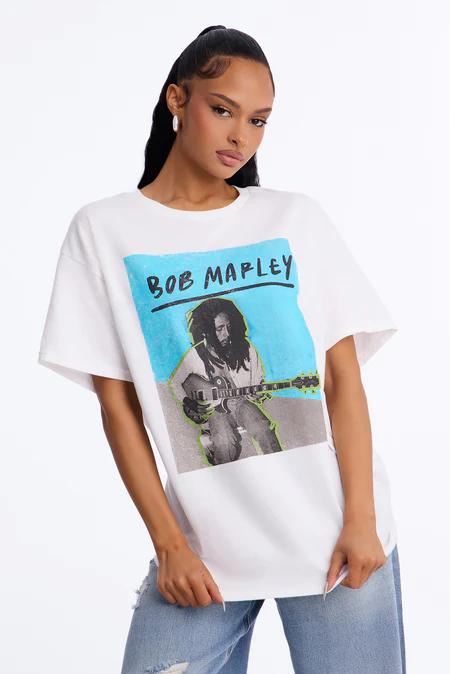 Woman in a white t-shirt featuring a blue graphic of Bob Marley playing guitar, with 'BOB MARLEY' text. She wears ripped blue jeans.