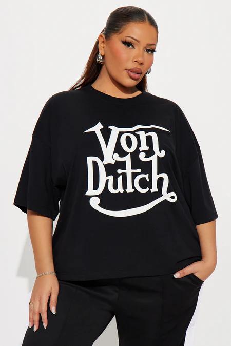 Mujer talla grande con camiseta gráfica Von Dutch negra y pantalones, ideal para outfits casuales modernos de tallas grandes.