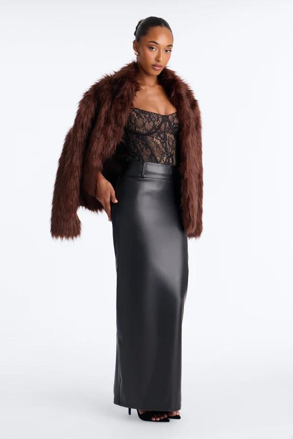 Woman wearing a brown faux fur jacket, black lace corset, and long leather maxi skirt, showcasing chic evening wear styling for fall.