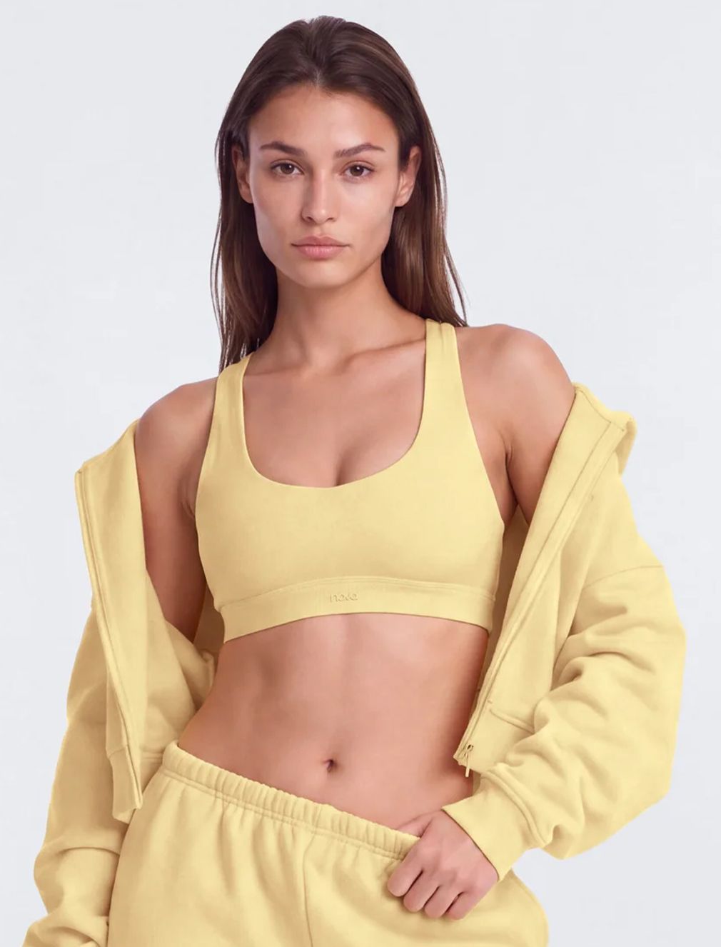 Woman wearing a pastel yellow activewear set with sports bra, zip hoodie, and sweatpants.