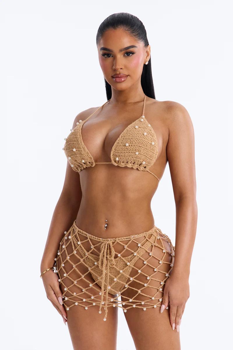 Model in beige pearl-beaded crochet bikini top and matching fishnet mini skirt, promoting chic summer beachwear.