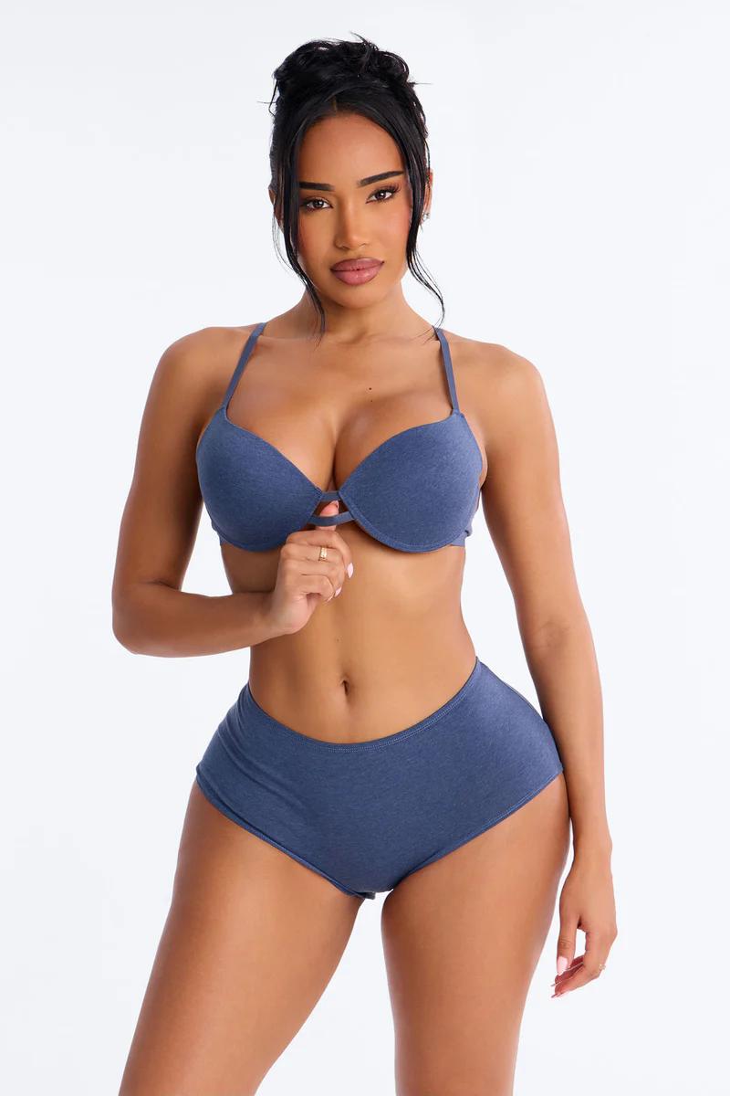 Woman in denim blue push-up bra and matching shorts set, holding clasp, promotes comfortable everyday lingerie.