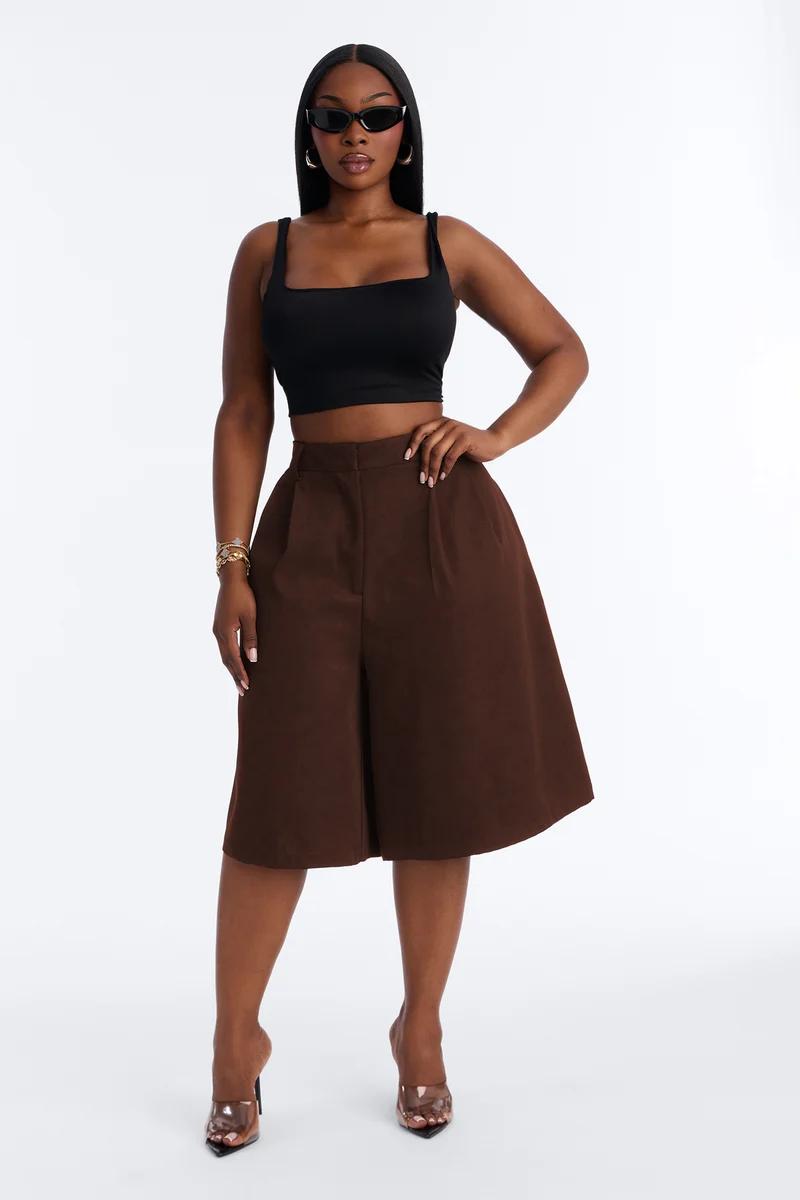 Black crop top and brown high-waisted culotte shorts styled with sunglasses and clear heels.