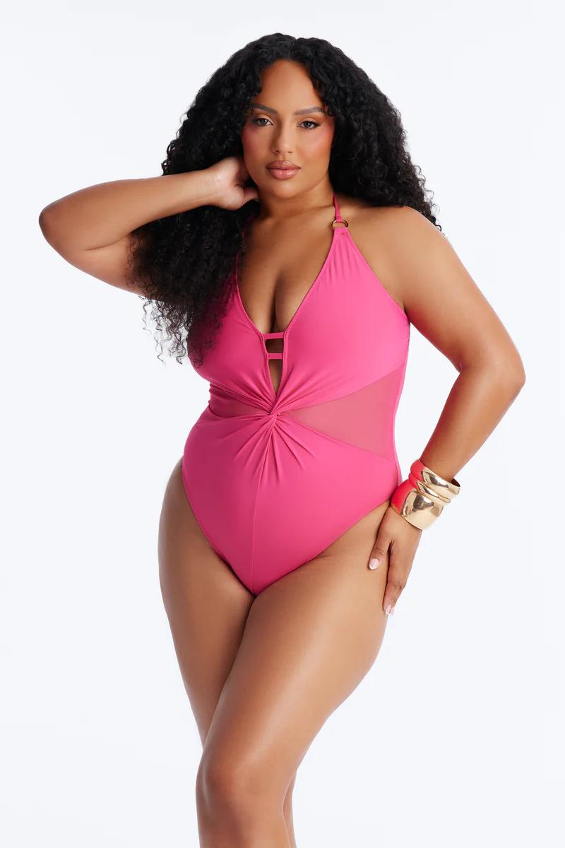 Plus size woman in hot pink mesh cutout twist-front one-piece swimsuit. Halter neck. Confident, curvy swimwear style.