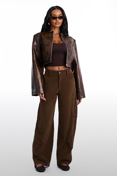 Model in a cropped brown leather jacket, matching top, and wide-leg corduroy pants, promoting a trendy monochrome fall streetwear outfit.