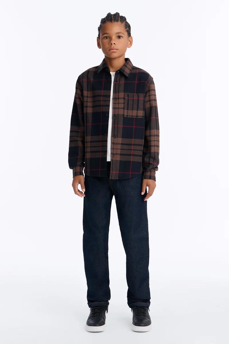 Camisa de franela a cuadros marrón para niño y jeans oscuros.