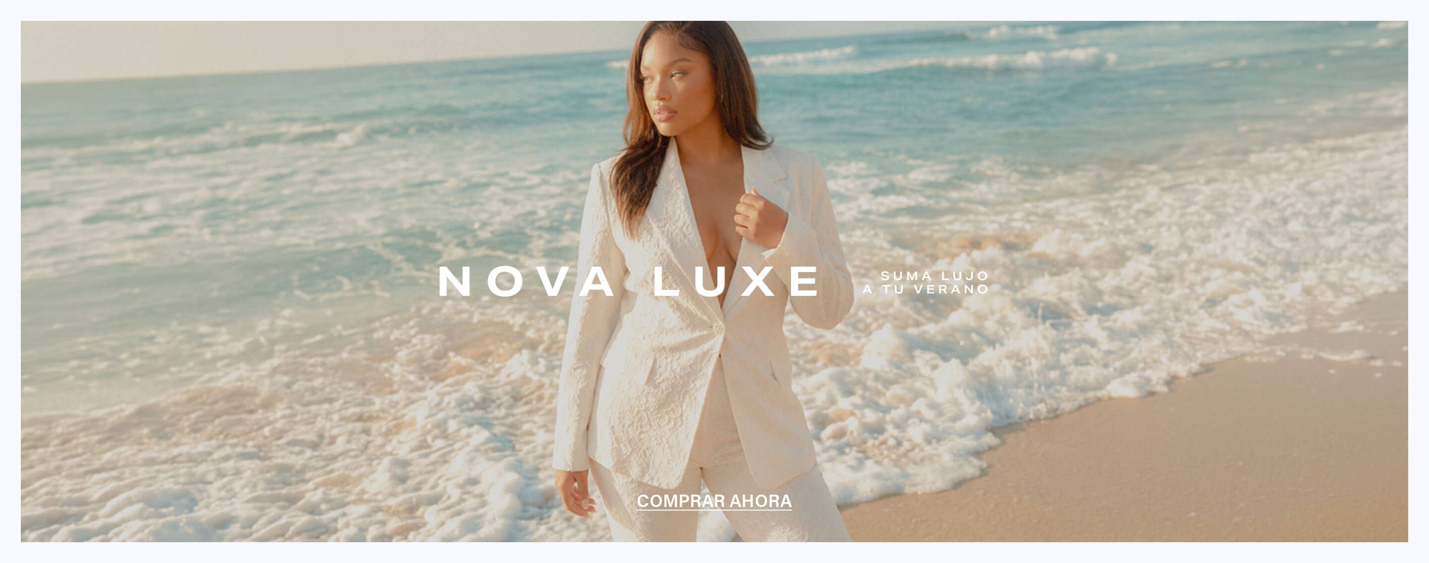 Mujer en elegante traje blanco texturizado en el océano, promocionando la colección de verano Nova Luxe de ropa de lujo. Compra ahora.