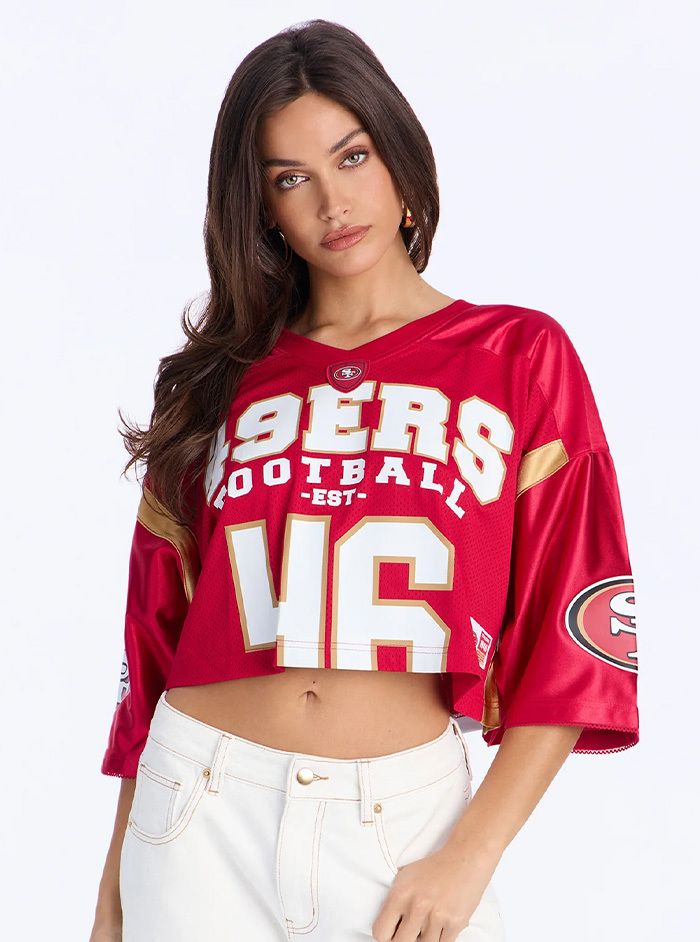 Mujer con jersey corto de los San Francisco 49ers y jeans blancos.