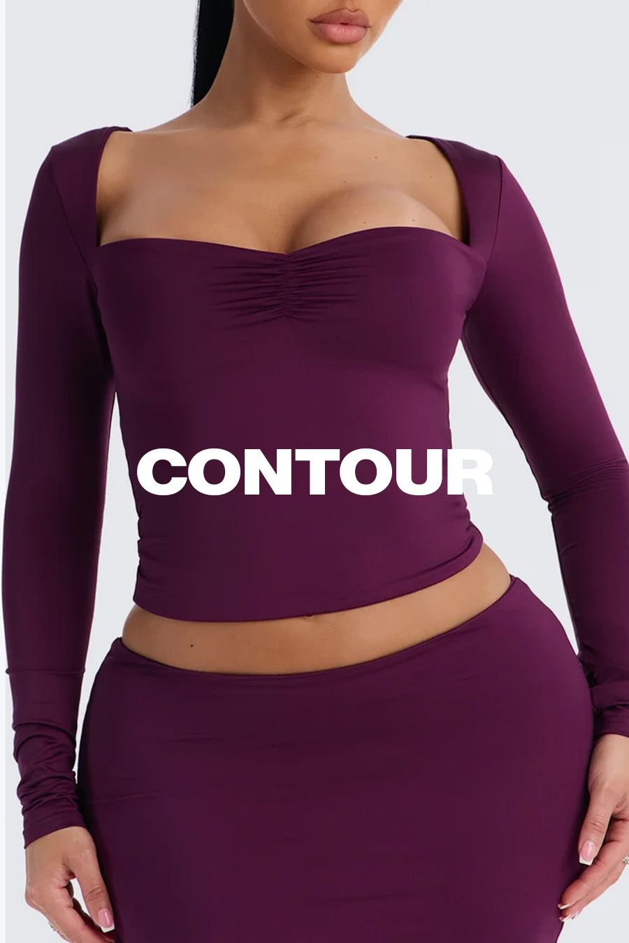 Model wearing a fitted deep plum purple long-sleeve sweetheart top and skirt promoting the new CONTOUR fashion collection.