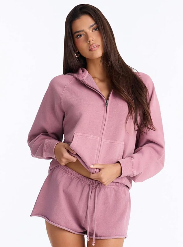 Woman models a dusty pink loungewear set with a zip-up hoodie and matching shorts, showcasing the brand's cozy new activewear.