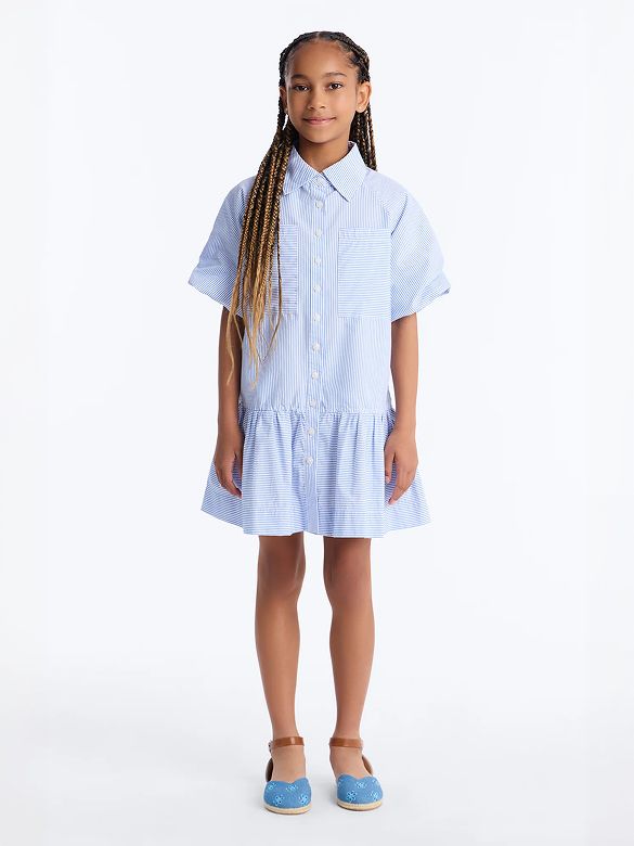 Smiling girl in a stylish blue and white striped shirt dress with short sleeves and a ruffled hem, showcasing our new spring kids' collection.