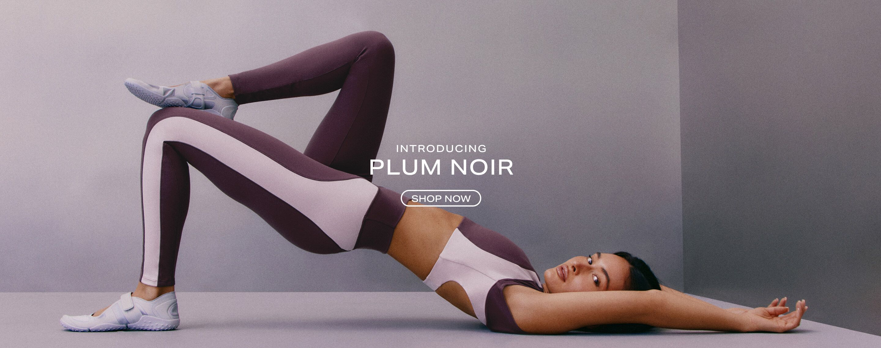 Two women posing in Nova Plum Noir activewear purple bodysuit, sports bra, and leggings.