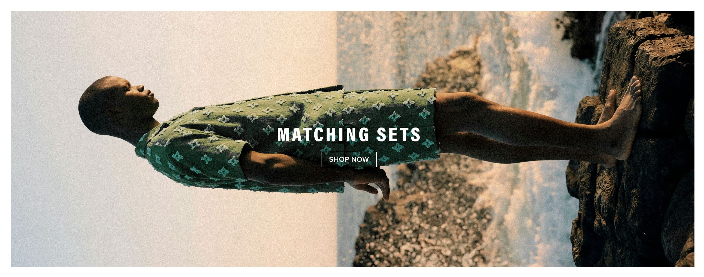 Man in green textured matching shirt and shorts set by the ocean. Shop new stylish men's summer matching sets now.