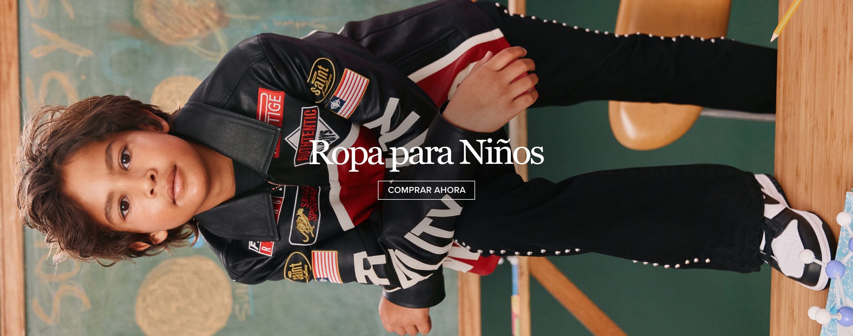 Joven con chaqueta negra, roja y blanca con parches, promocionando nueva colección de ropa para niños. Compra ahora.