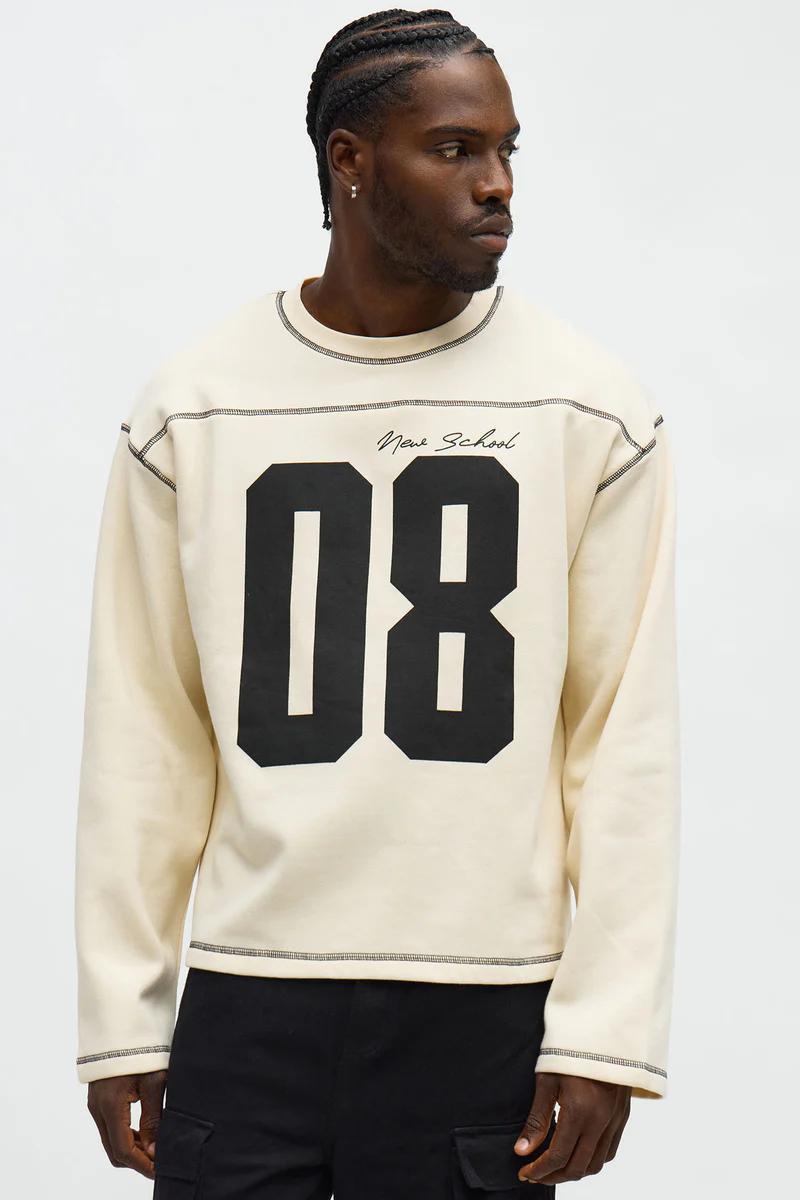 Man in a cream "New School 08" sweatshirt featuring exposed stitching. Showcasing new arrivals in men's casual long-sleeve tops.