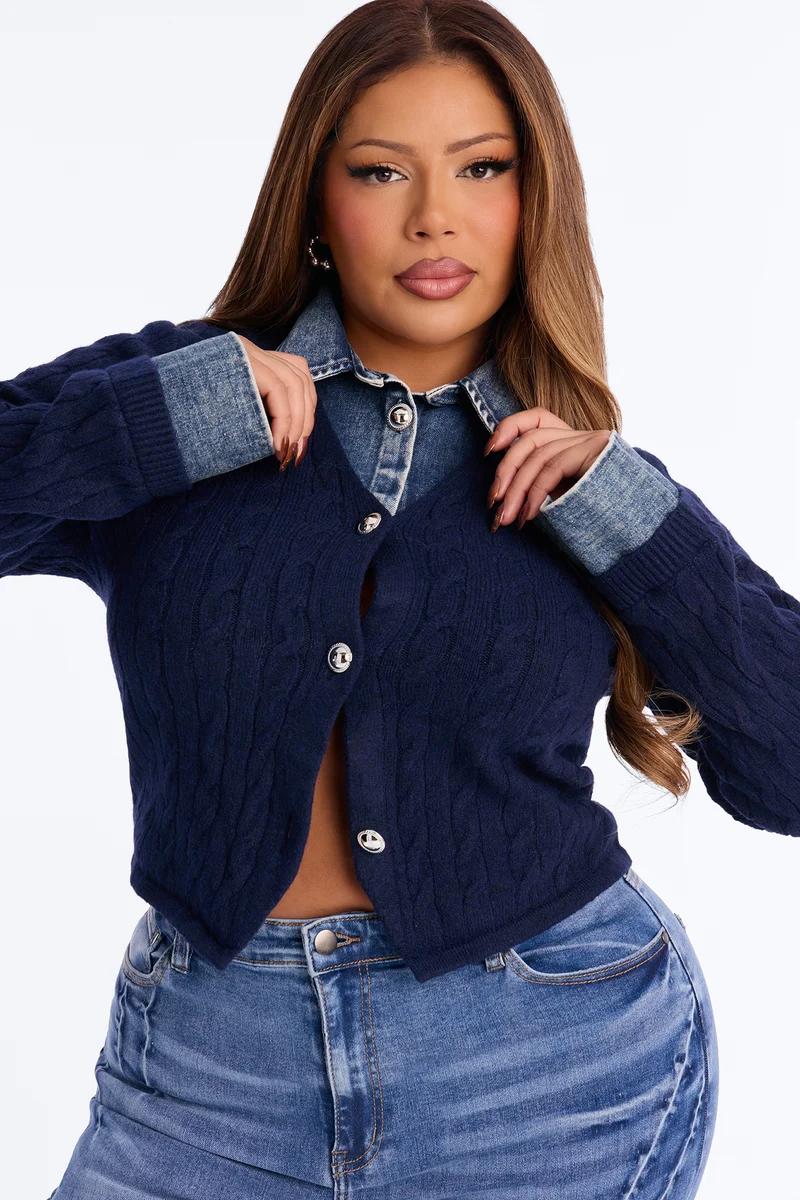 Mujer de talla grande con cárdigan de punto trenzado azul marino sobre camisa de mezclilla.