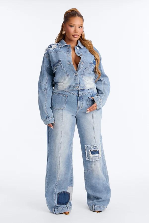 Mujer posando con chaqueta de mezclilla azul claro y jeans anchos de parches a juego para promocionar la nueva colección de moda curvy.