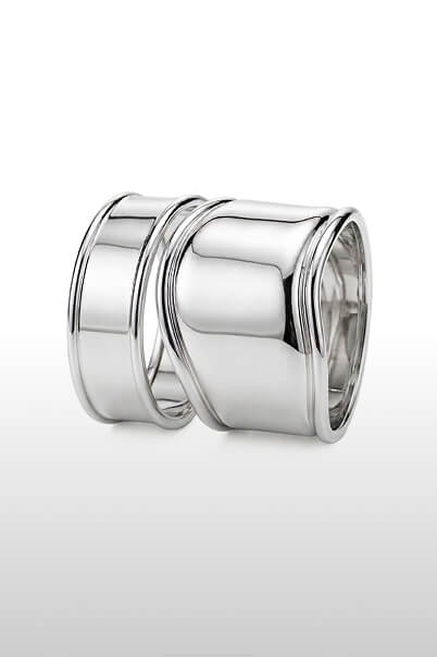 Elegante servilletero de metal plateado con diseño curvo y pulcro. Accesorio moderno perfecto para mesas sofisticadas.