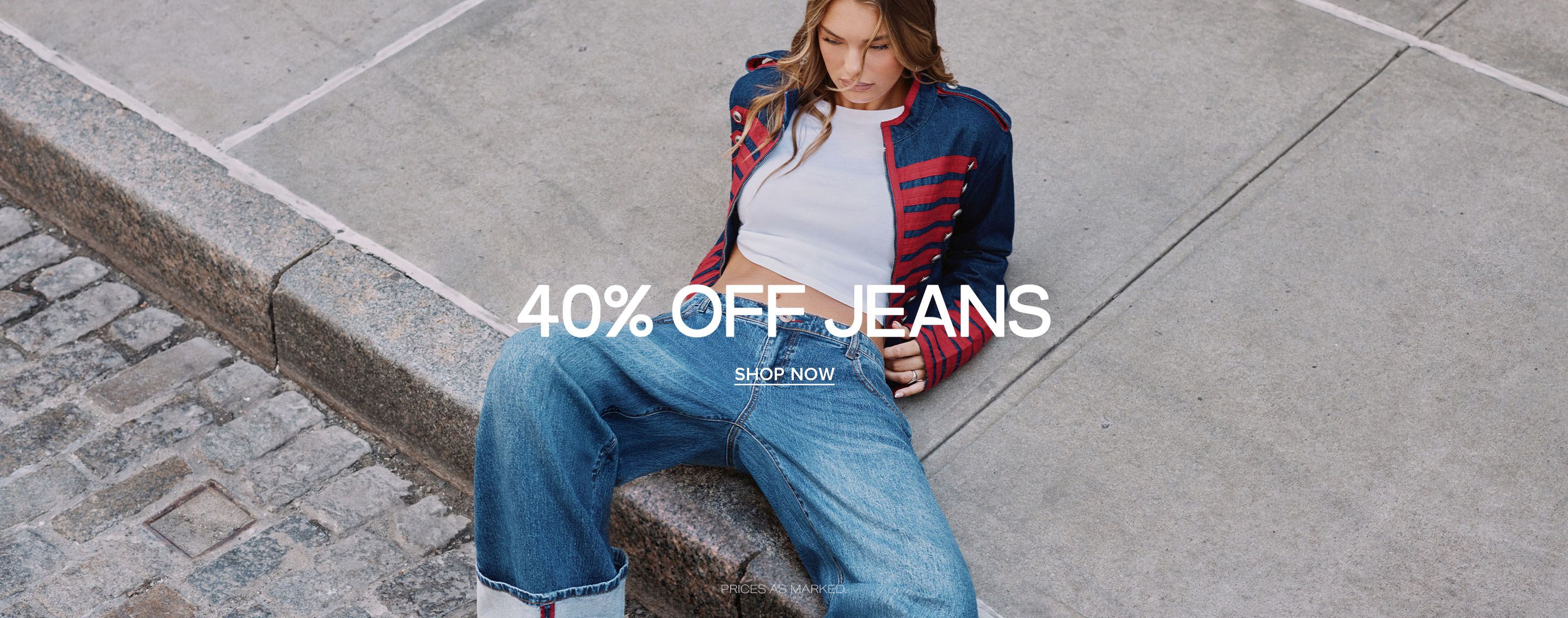 Woman on concrete steps wearing wide-leg cuffed denim jeans and a blue jacket. Promo text reads: 40% off jeans, advertising a denim sale.
