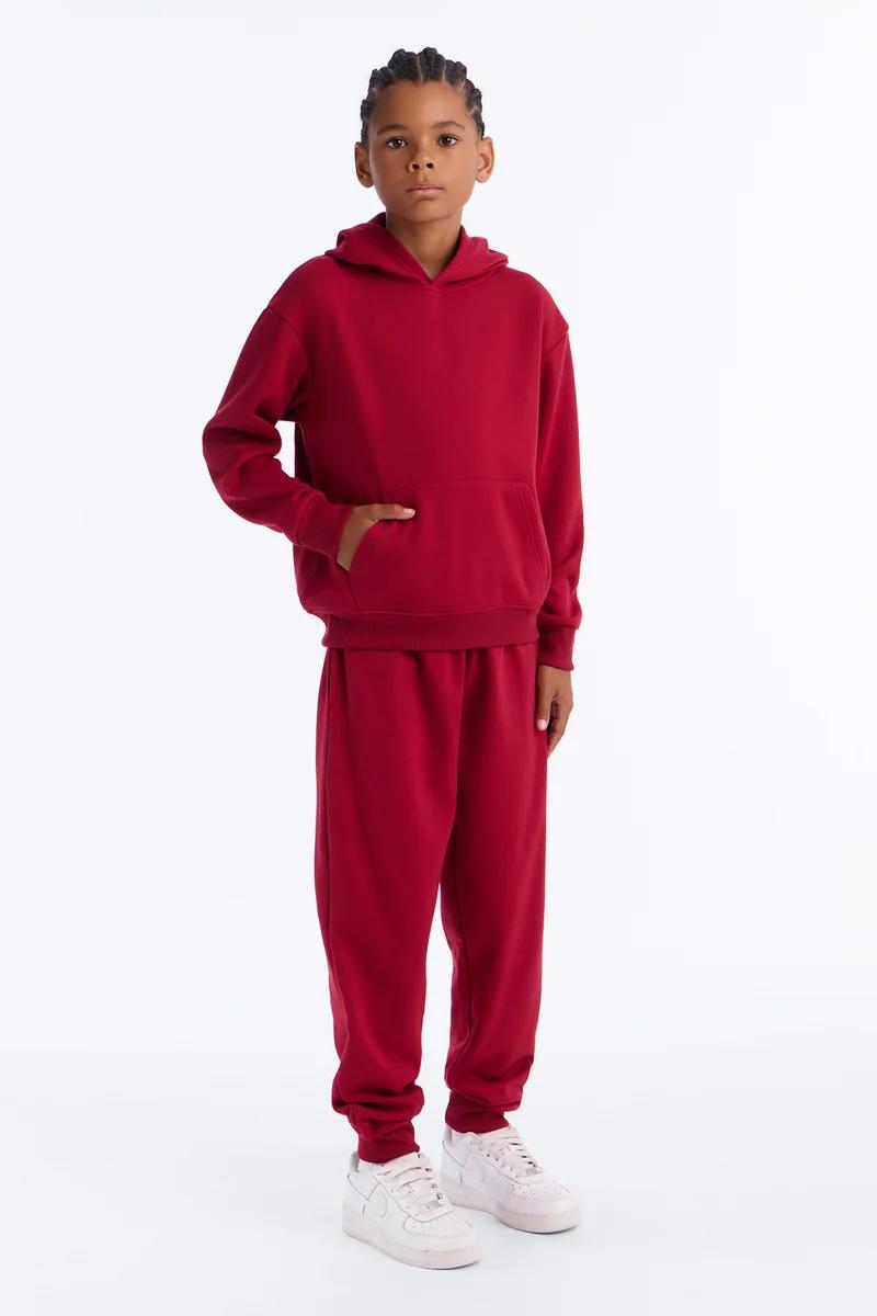 Boy wearing a kids red hoodie and matching sweatpants tracksuit set.