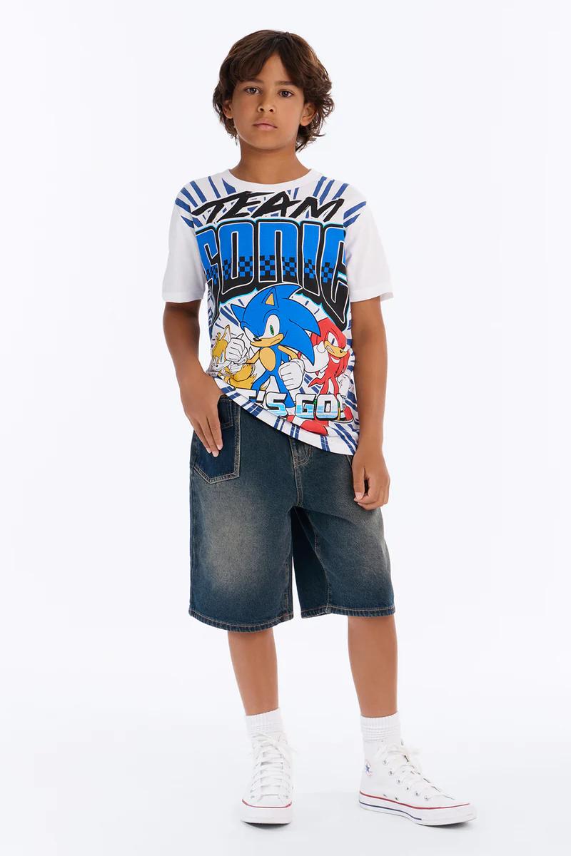 Boy in Team Sonic t-shirt with Sonic, Tails, Knuckles, denim shorts, & white high-top sneakers. Kids' apparel.