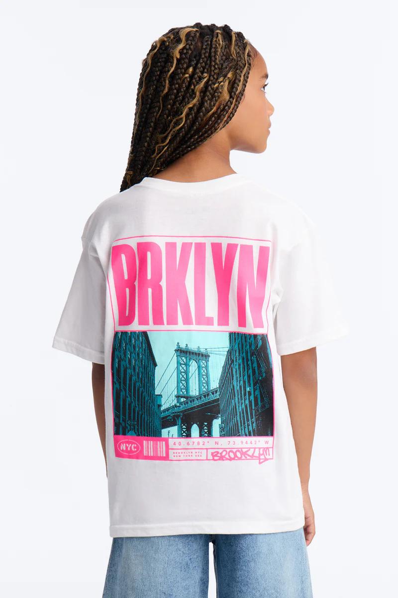 White BRKLYN graphic tee with NYC Manhattan Bridge design. Youth fashion for casual wear.