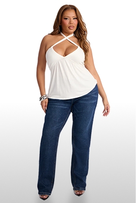 Plus size model in a chic white crisscross halter top and dark wash straight leg jeans, promoting trendy curvy fashion.