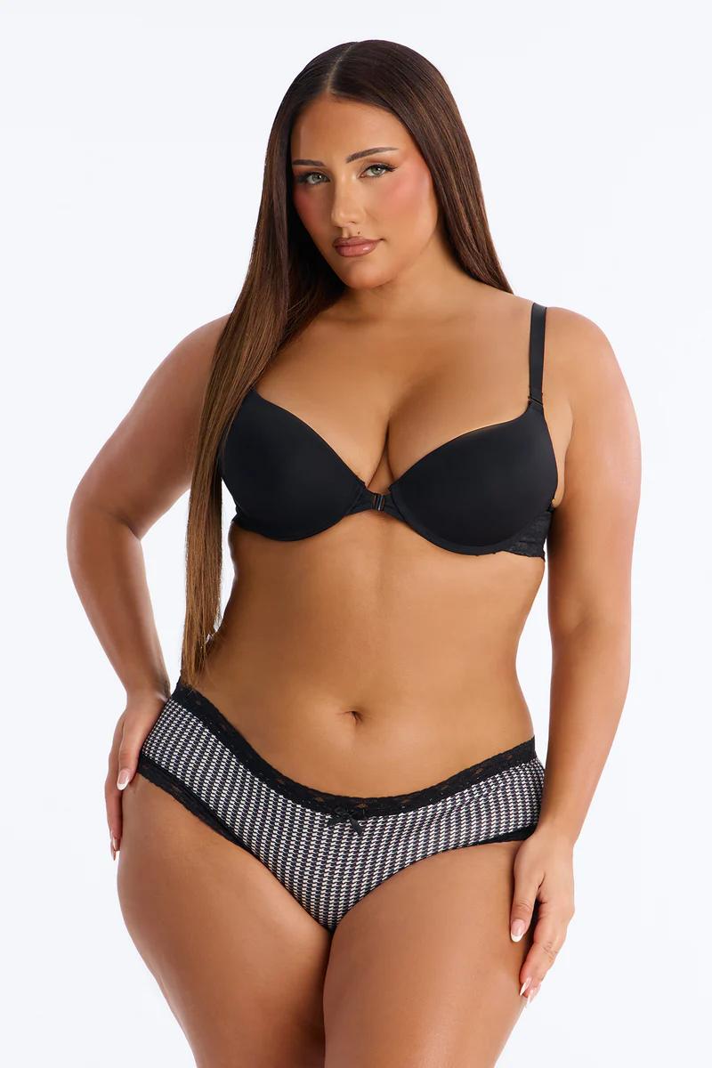 Woman in a black push-up bra and stylish black and white houndstooth panties with lace trim. Showcases comfortable lingerie.
