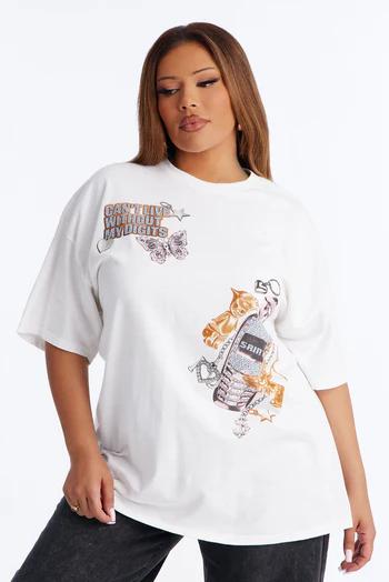 Woman in an oversized white t-shirt featuring "CAN'T LIVE WITHOUT MY DIGITS" text, a pink butterfly, and a metallic flip phone design with golden chains.