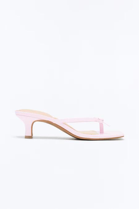 Elegante sandalia de tacón bajo rosa claro con puntera cuadrada, tira de dedo, delicado detalle de lazo y suela marrón.