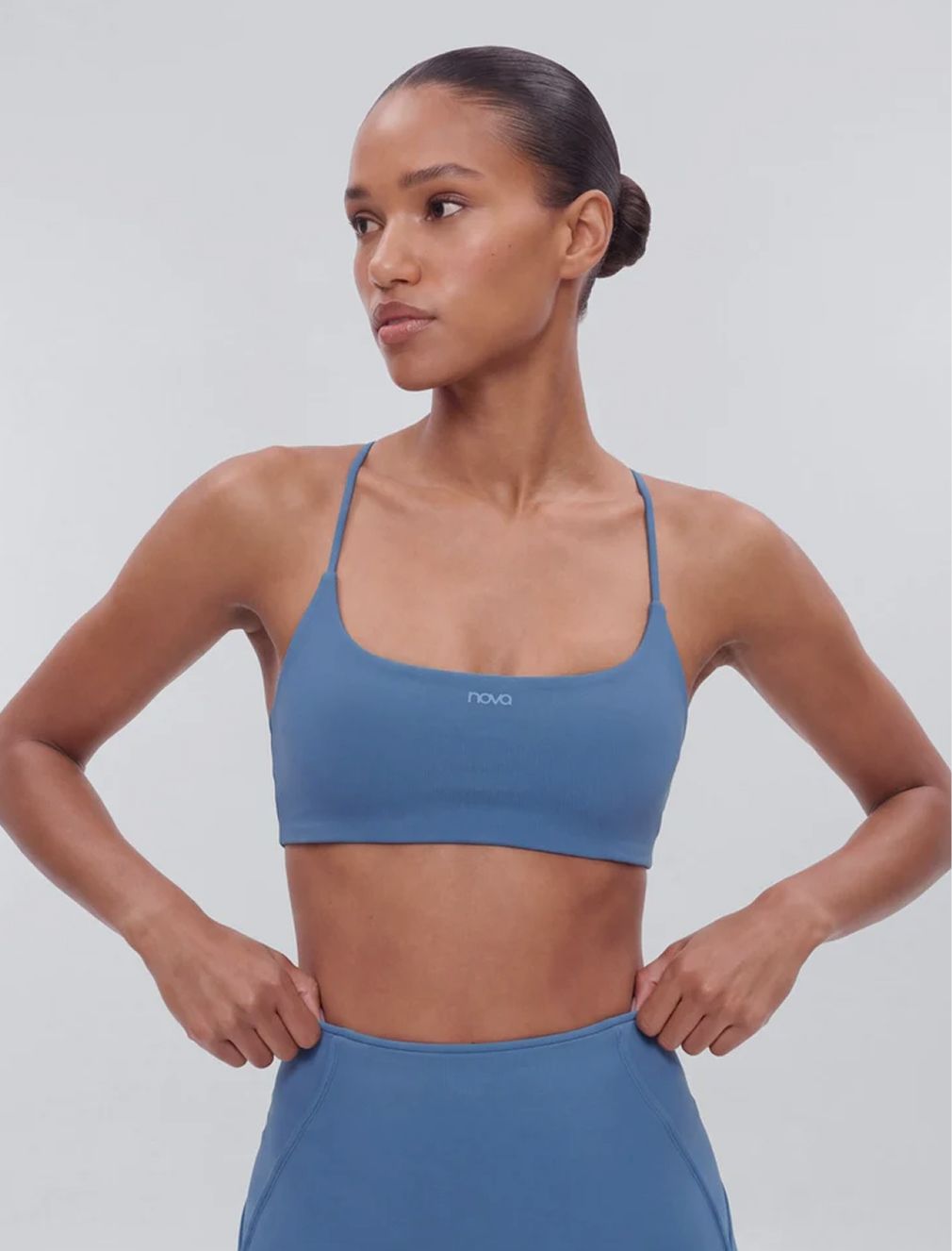 Woman in a blue Nova sports bra and matching high-waisted activewear leggings.