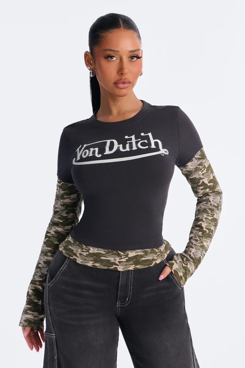 Woman wearing a black Von Dutch long sleeve top with layered camouflage sleeves.