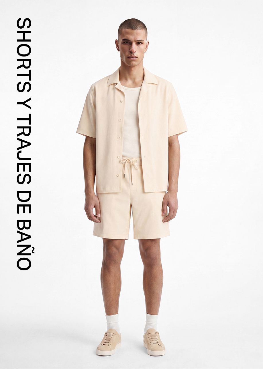 Hombre con camisa beige claro de manga corta, camiseta y shorts con cordón a juego, mostrando moda de shorts y bañadores masculinos.