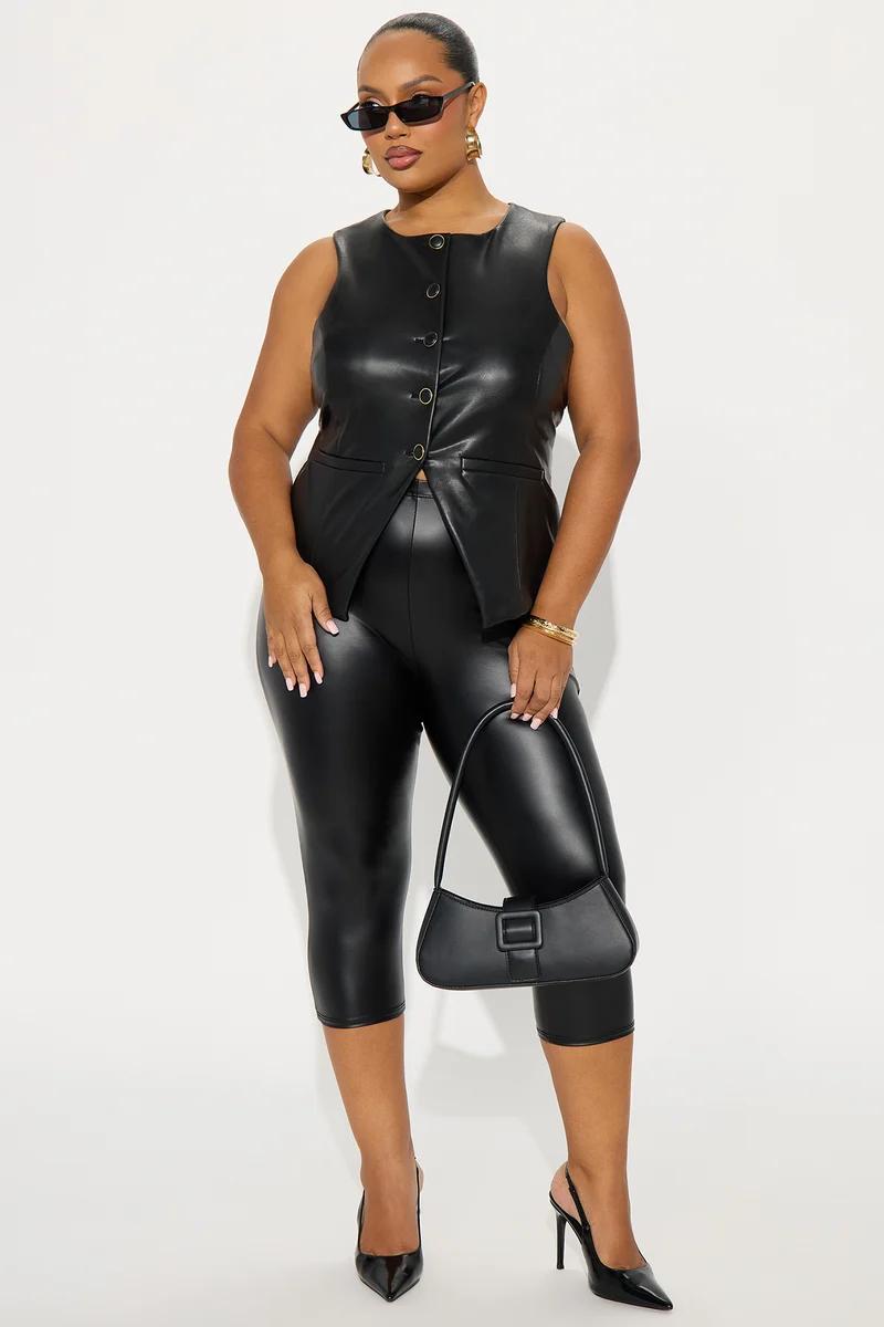 Modelo de talla grande con chaleco de cuero sintético negro y leggings ajustados, luciendo un bolso para promover moda curveada moderna.