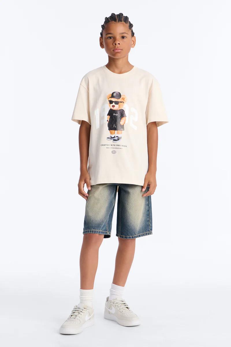 Niño con camiseta gráfica de Sonic the Hedgehog crema, jeans azules claros y zapatillas blancas, para línea de ropa infantil.