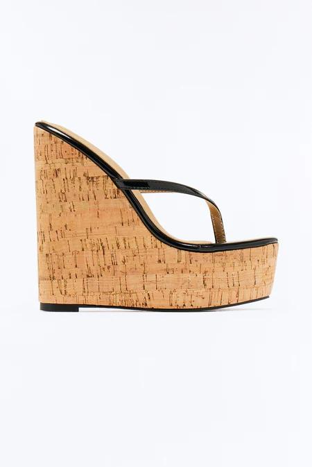 Black patent leather thong-style wedge sandal with a high natural cork platform and heel, seen from the side on white.